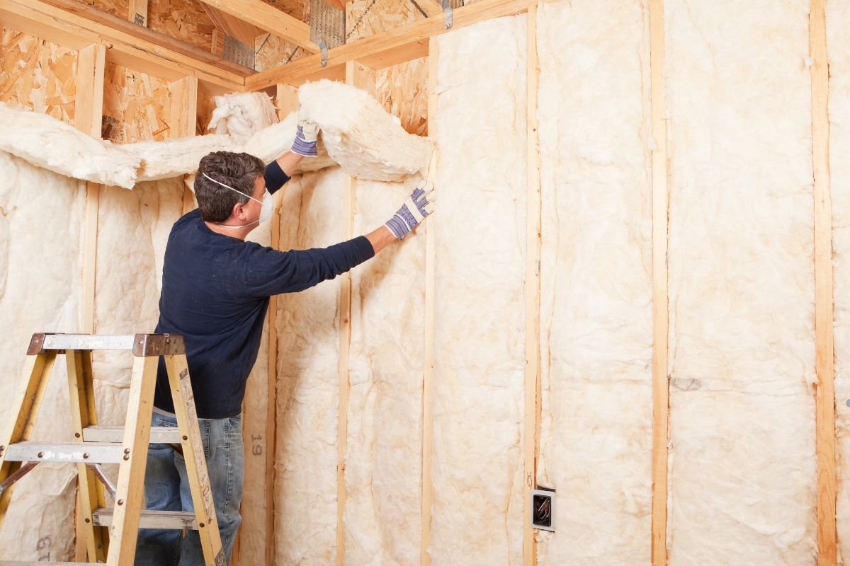 A man installs insulation in a room, demonstrating professional insulation service for improved energy efficiency.