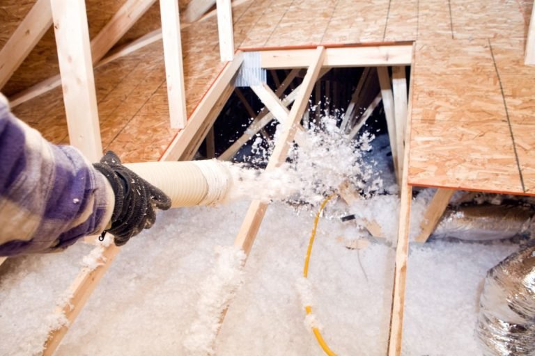 A person operates a vacuum cleaner to remove insulation during an insulation service.