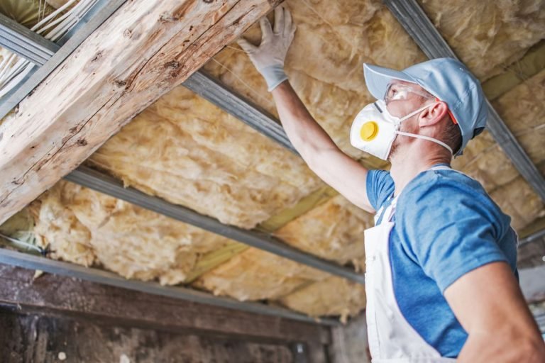 A technician installing insulation in an attic, showcasing tools and materials used for effective thermal protection.