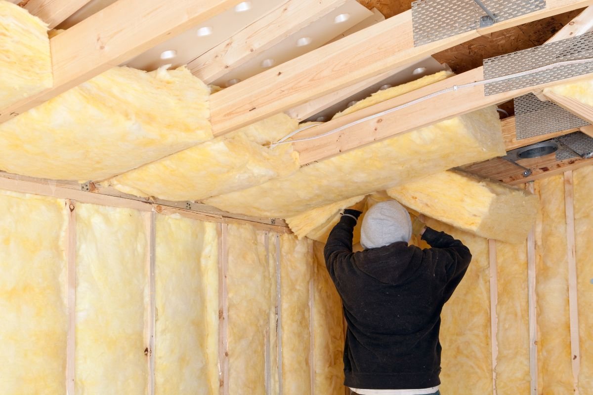 A man installs insulation in a room, demonstrating an insulation service for improved energy efficiency.